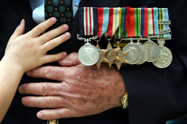 The hand of Zac Perry, 5, reaches for the medals worn by Rats of Tobruk veteran John Taylor, after the Remembrance Day ceremony at the Shrine of Remembrance, Brisbane, in 2004.