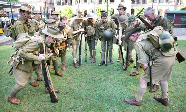 Mark Simm (right) plays a game of two-up after the march with mates. Anzac Day March in the Brisbane CBD. Pic: Peter Wallis